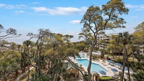 A resort with a swimming pool, palm trees, and a view of the ocean. - 2418 Windsor II - Oceanfront 4-Bed/4-Bath Villa - Fantastic Wrap Around Balcony! (Hilton Head Island)
