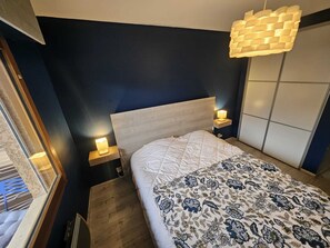 A bedroom with a bed, bedside lamps, a wooden headboard, and a hanging light fixture. - Beautiful apartment with magnificent view of Mont Blanc (Sallanches)