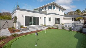Ett modernt hus i två våningar med en välskött gräsmatta och en golfbana.