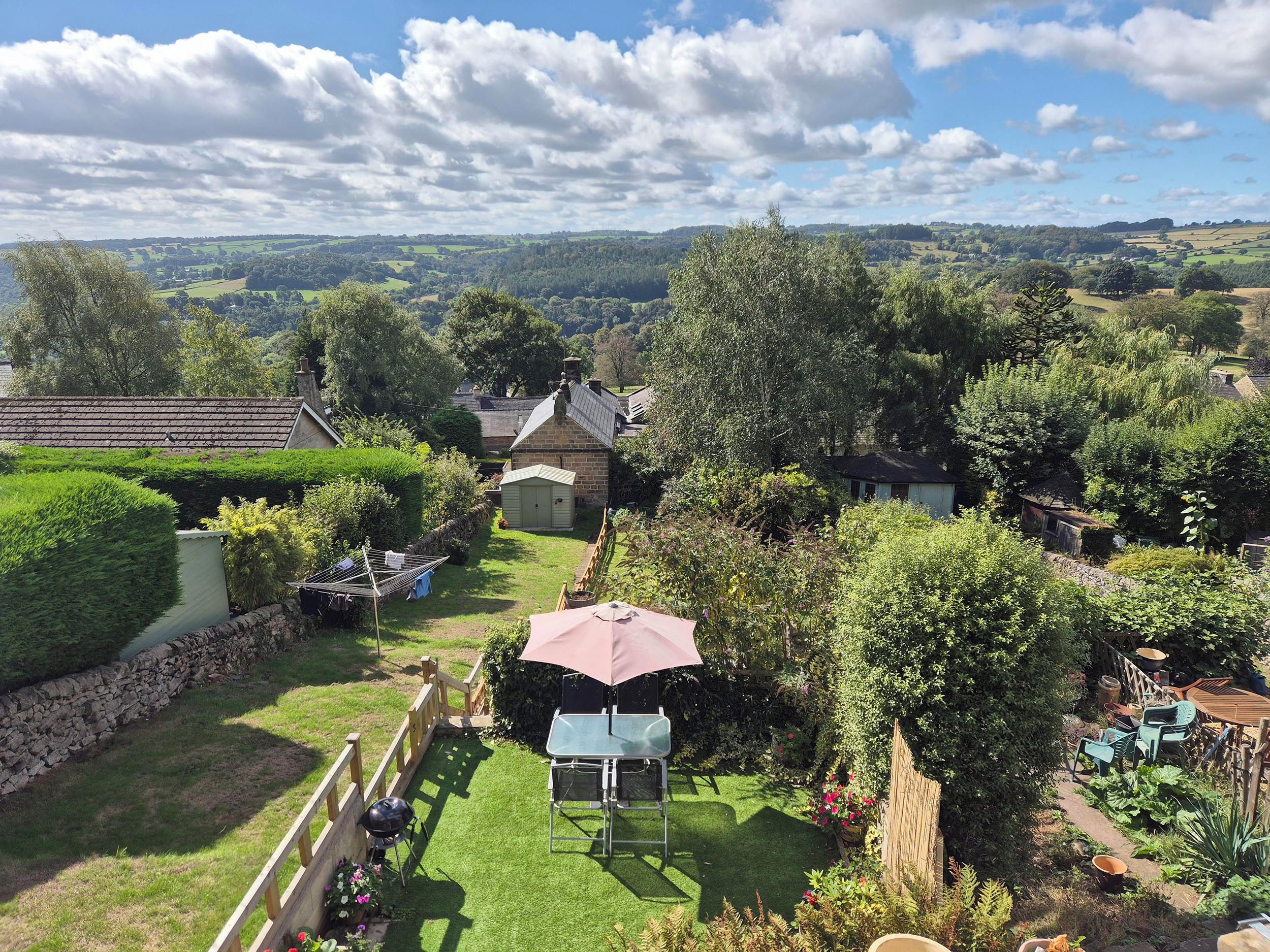 A residential property with a well-maintained lawn, a barbecue area, and a view of the surrounding countryside.