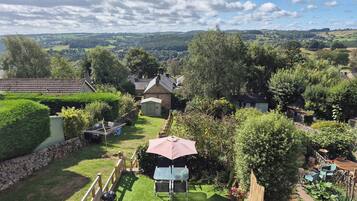 A residential property with a well-maintained lawn, a barbecue area, and a view of the surrounding countryside.
