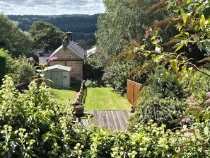 A garden with a shed, a wooden fence, and a lawn.