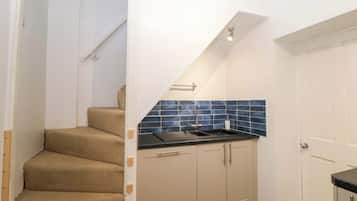 A kitchen with a black countertop, beige cabinets, and blue tiles.