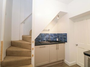 A kitchen with a black countertop, beige cabinets, and blue tiles. - Natures Retreat (Matlock)