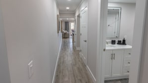 A hallway with a kitchen area, white walls, and a tiled floor. - 112 Arrowhead Unique Lakefront 2br At Kingston 2 Bedroom Condo (Myrtle Beach)