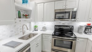 A modern kitchen with white cabinets, stainless steel appliances, a dishwasher, and a microwave. - 112 Arrowhead Unique Lakefront 2br At Kingston 2 Bedroom Condo (Myrtle Beach)