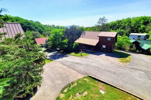 A residential area with a large driveway, a wooden house with a red roof, and a metal shed. - Soaring Eagle 4 Bedroom Cabin (Pigeon Forge)