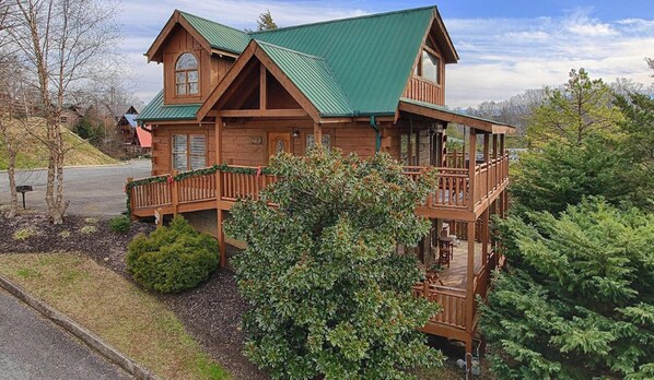 A wooden cabin with a green roof, a balcony, and a small porch. - Soaring Eagle 4 Bedroom Cabin (Pigeon Forge)