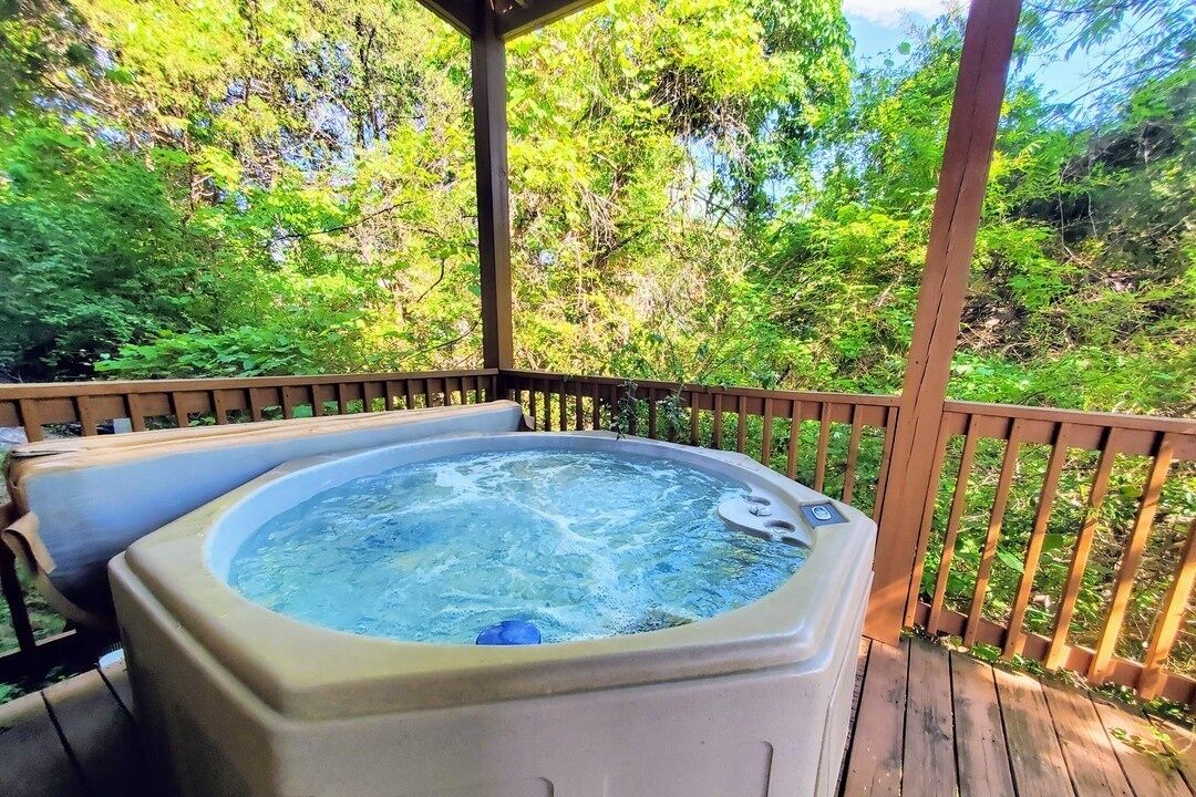 A hot tub on a wooden deck with a natural forest backdrop.