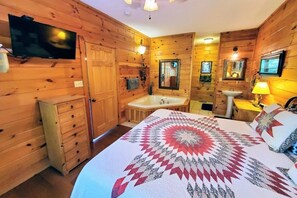 A wooden-paneled room with a bed, a TV, a sink, and a mirror. - Soaring Eagle 4 Bedroom Cabin (Pigeon Forge)