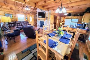 A log cabin interior with a living room, dining area, fireplace, television, and kitchen. - Soaring Eagle 4 Bedroom Cabin (Pigeon Forge)