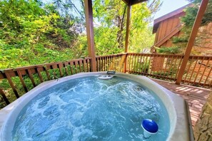 A hot tub with a wooden deck and a wooden fence, surrounded by greenery. - Soaring Eagle 4 Bedroom Cabin (Pigeon Forge)