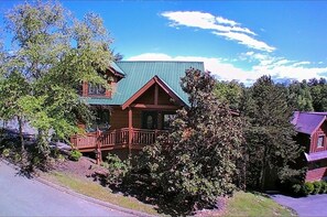 A two-story log cabin with a green metal roof, a wooden porch, and a small front deck. - Soaring Eagle 4 Bedroom Cabin (Pigeon Forge)
