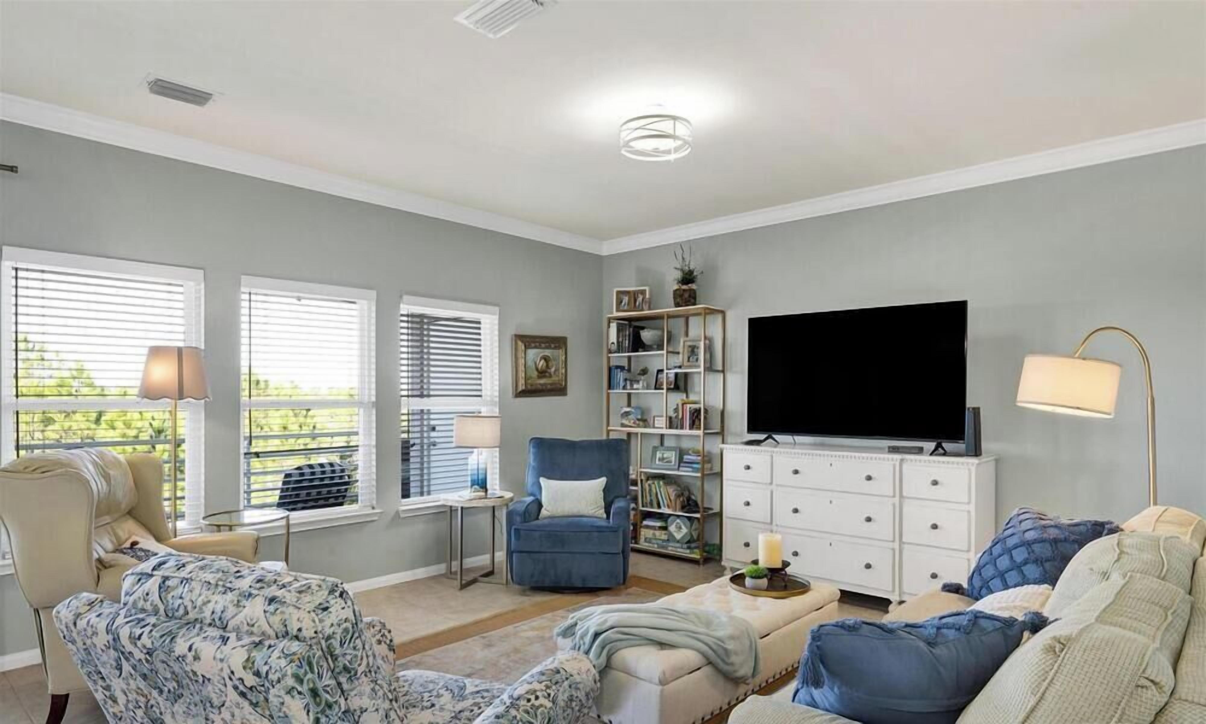 A living room with a sofa, armchair, TV, bookshelf, and a lamp.