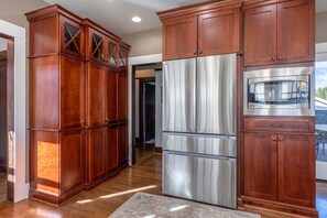 A kitchen with wooden cabinets, a stainless steel refrigerator, and a microwave. - State Of Chill 4 Bedroom Home (Hood River)