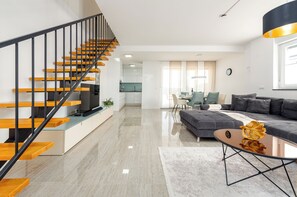 Ein moderner Wohnraum mit Treppe, Essbereich und Sofa.
