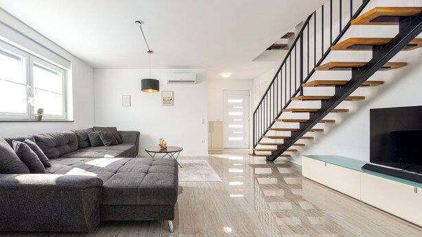 A modern living room with a sectional sofa, a glass coffee table, a black TV on a glass shelf, a staircase with wooden steps, and a white door in the background. - New vacation home in Nin, 100m to the beach l 3 bedrooms l 2 bathrooms l 6 pers. l All-inclusive. (Nin)