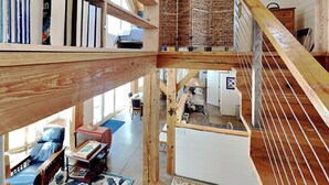 Un intérieur en bois à plusieurs niveaux, comprenant un escalier, un coin cuisine et un espace salon avec vue.