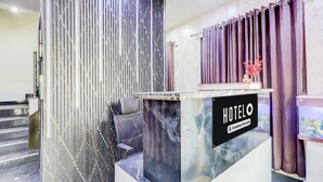 En hotelreception med en marmorbordplade, en stribet væg og en lilla gardin.
