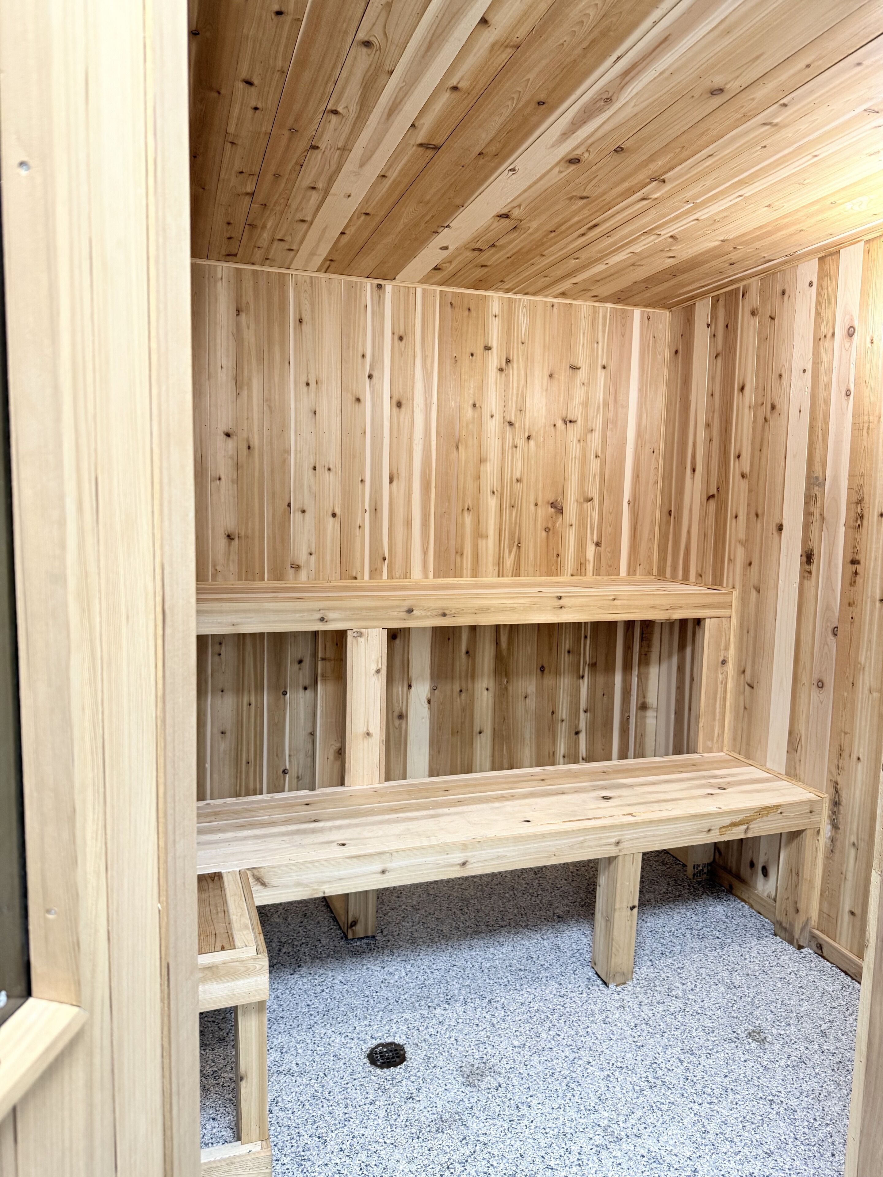 A wooden sauna with benches and a sloped ceiling.