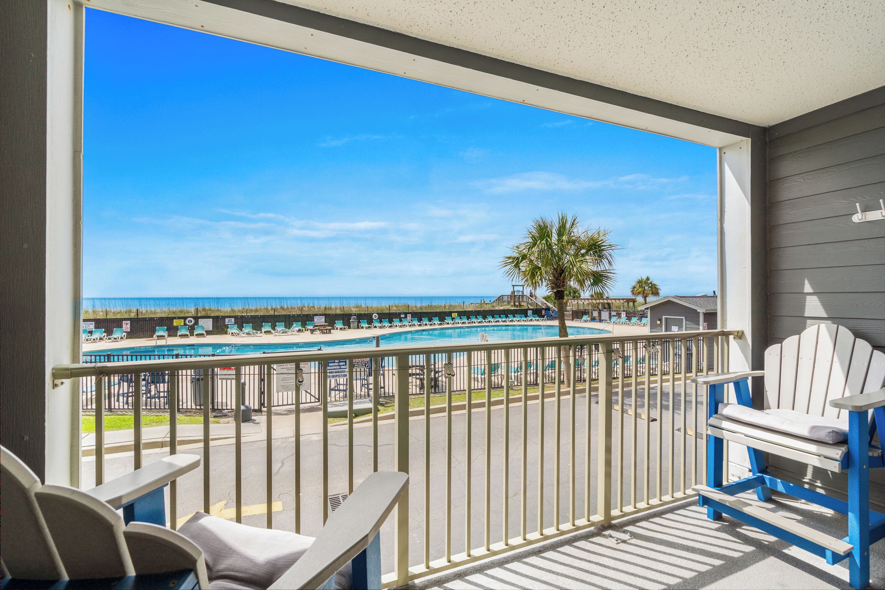 Un balcon avec vue sur une piscine et une plage.