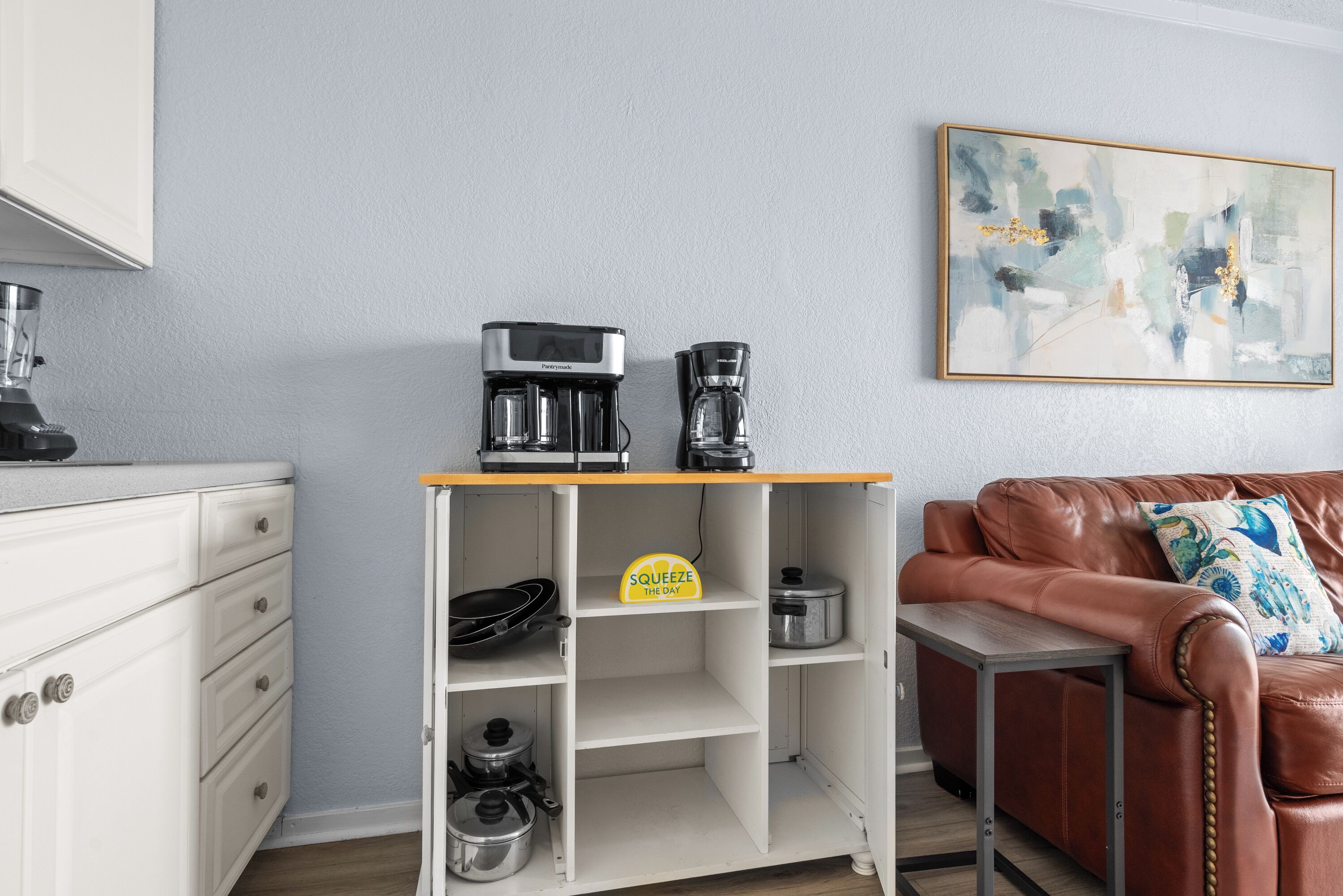 Une petite cuisine équipée d’une machine à café, d’une poêle, d’une casserole et d’une pancarte sur laquelle est écrit : « PROFITEZ DE CHAQUE INSTANT ».