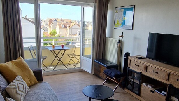 En stue med sofa, fjernsyn, lille bord og stol.