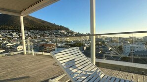 Ein Balkon mit Blick auf eine Stadtlandschaft und eine Hügelkette.