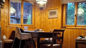 En inredning med träpanel, ett matbord, stolar, en bänk och ett fönster med utsikt över en balkong.