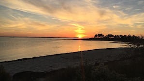 Auringonlasku tyynen vesistön yllä, kauempana näkyy rantaviiva.