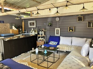 Ein gemütlicher Wohnbereich mit einer Couch, einem Couchtisch und einer Bar mit verschiedenen Gegenständen.