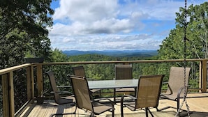 Eine Holterrasse mit Gartenmöbeln, darunter Stühle und ein Tisch, mit Blick auf eine reizvolle Landschaft.