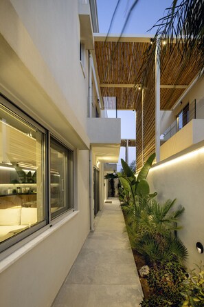 A modern building with a covered walkway, large windows, and indoor plants. - Atlantis Homes 1, By Hellocrete (Rethymno)