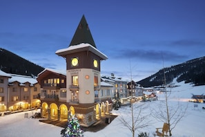 A lodge with a clock tower, multiple buildings, and a snowy landscape.
