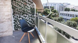 A balcony with a chair, a mesh screen, and a view of buildings. - Athens Riviera 2BR Apartment by ΜΡS (Kallithea)