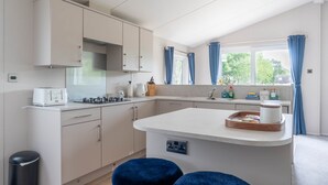 A modern kitchen with a central island, built-in appliances, and a window with curtains.