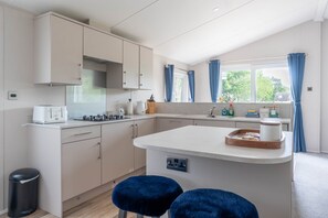 Eine moderne Küche mit einer zentralen Kochinsel, eingebauten Geräten und einem Fenster mit Vorhängen.