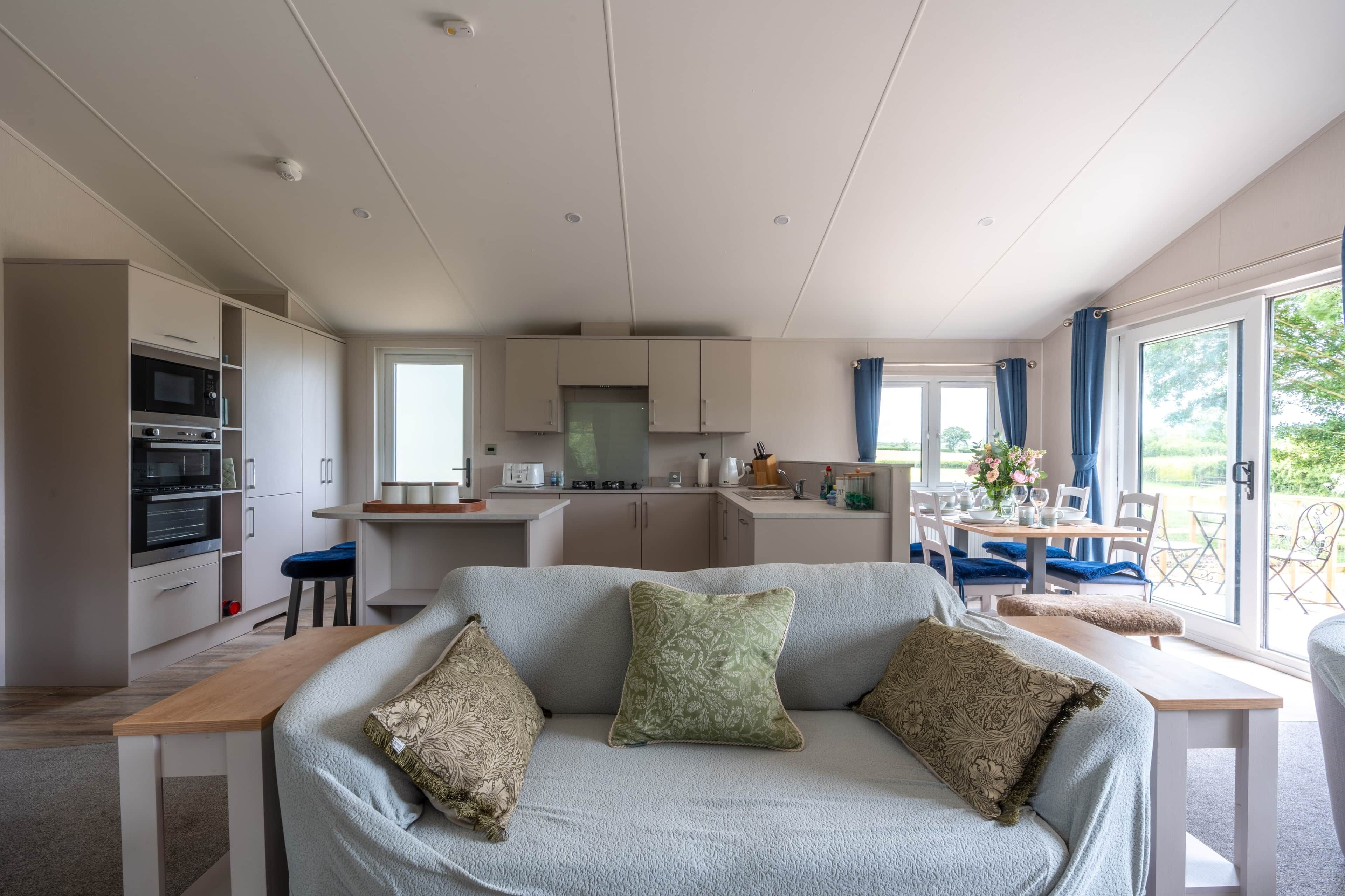 A living room with a sofa, a dining table, and a kitchen area with cabinets and appliances.
