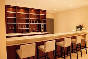 A kitchen with a marble countertop, wooden shelving, and bar stools.