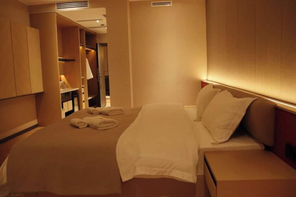 Hotellihuone, jossa on sänky, yöpöytä ja vaatekaappi.
