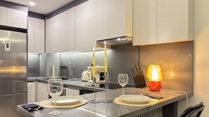 Eine moderne Küche mit einer zentralen Kochinsel, Edelstahlgeräten und einem Essbereich mit Kerze und Gläsern.