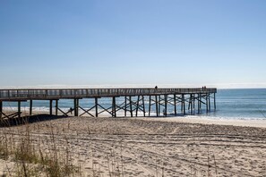 Eine hölzerne Steg, der sich ins Meer erstreckt, mit Menschen, die darauf entlanggehen.