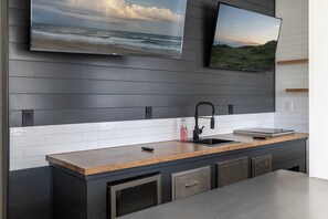 Eine moderne Küche mit einer Holzauskładung, einem schwarzen Wasserhahn, einem eingebauten Backofen und einem Fernseher über der Spüle.