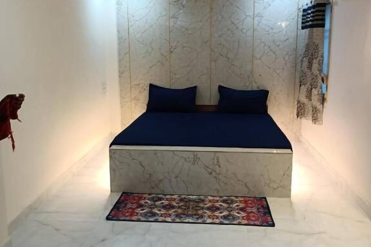 A bedroom with a bed, a ceiling fan, and a patterned rug.
