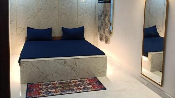 A bedroom with a bed, a large mirror, and a ceiling fan. - Hotel HCB (Brahmapur)