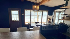 A kitchen with a large island, a dining area with chairs, a view of the outdoors, and a hanging light fixture. - Lake Carlos Getaway w/Sandy Beach, Dock, Lift & Stunning Sunsets 3-bedroom house (Carlos)