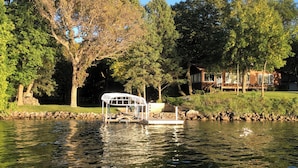 A lake with a dock, a covered seating area, and a house in the background. - Lake Carlos Getaway w/Sandy Beach, Dock, Lift & Stunning Sunsets 3-bedroom house (Carlos)