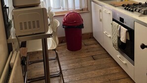 Una cocina compacta con estufa, lavamanos y ventana con cortinas.