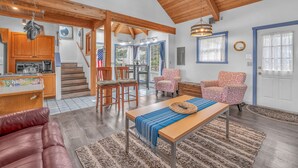 A spacious living area with a wooden ceiling, a dining table, and a kitchen area with wooden cabinets and a stove. - Lincoln City Retreat: Private Hot Tub, Game Room, Easy Beach Access (Lincoln City)