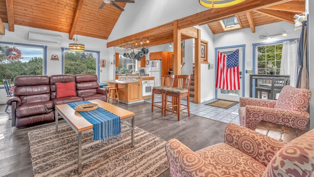 A spacious living room with a leather sofa, patterned armchairs, a wooden coffee table, and a kitchen in the background. - Lincoln City Retreat: Private Hot Tub, Game Room, Easy Beach Access (Lincoln City)